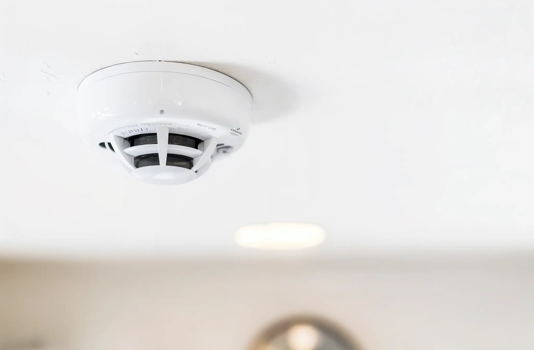 Smoke alarm subtly installed on the ceiling of a luxury apartment with custom molding and designer lighting.