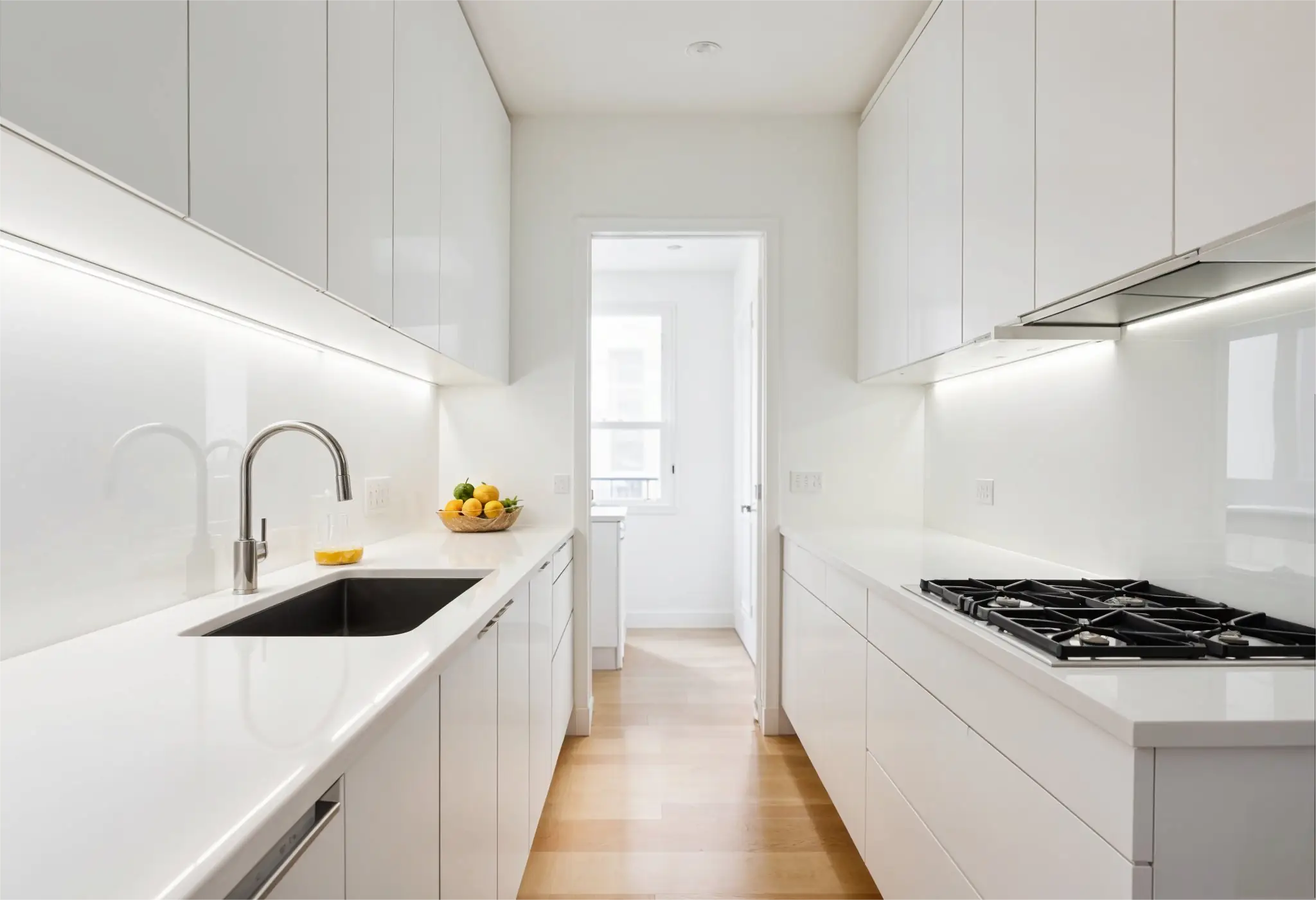 Full-height white glass backsplash in a compact galley kitchen.