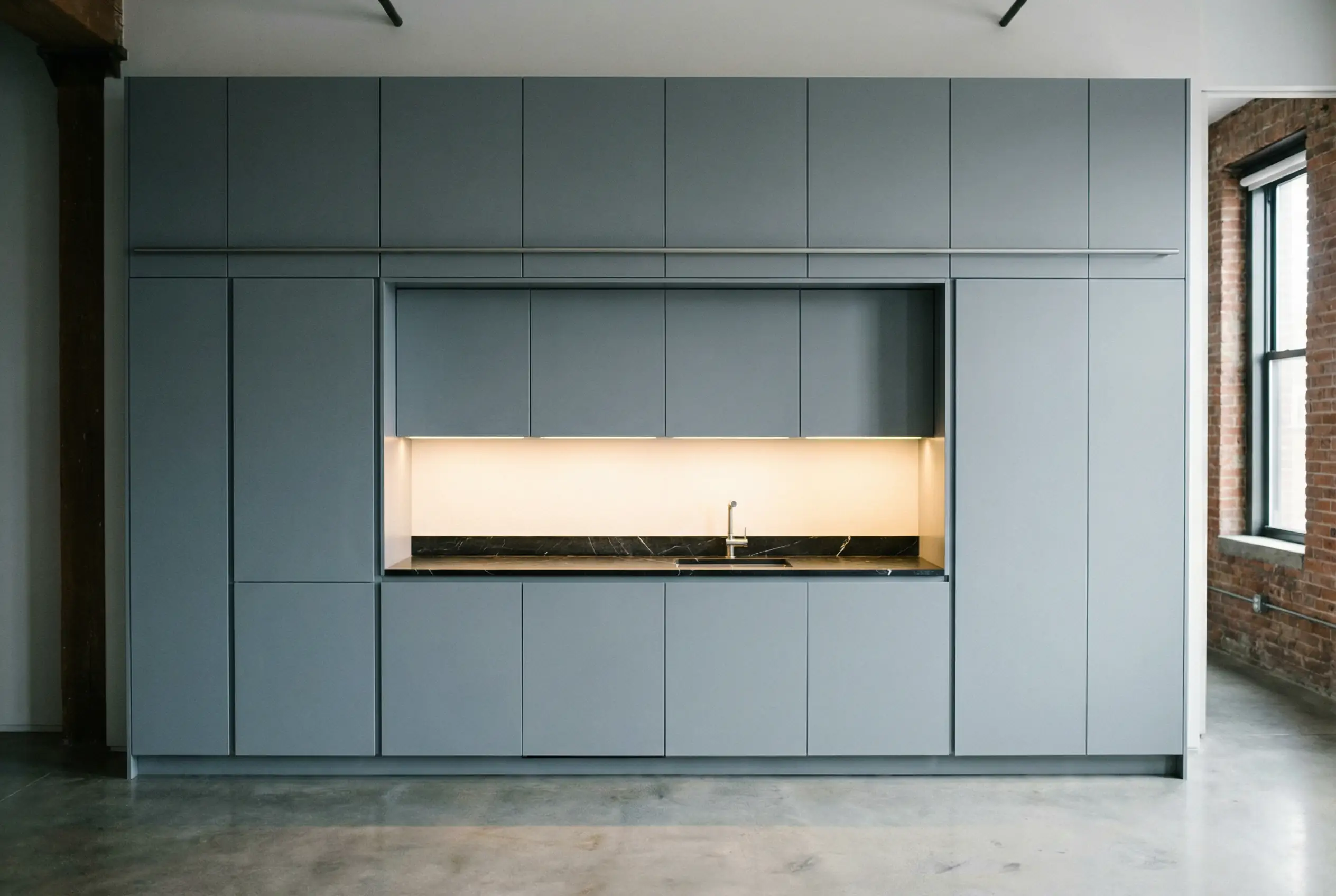 Seamless integrated kitchen wall grey lacquer cabinetry with hidden appliances and marble countertop in Manhattan loft