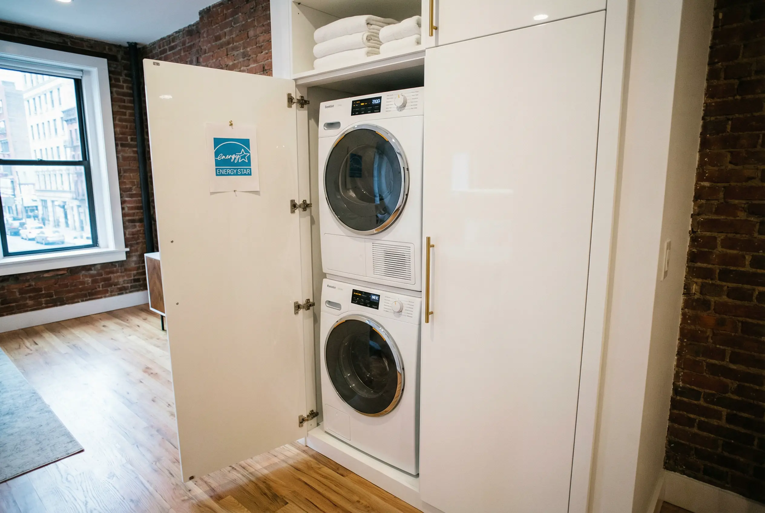 Stacked Energy Star 2026 compliant heat pump dryer and front-load washer in Manhattan apartment laundry closet